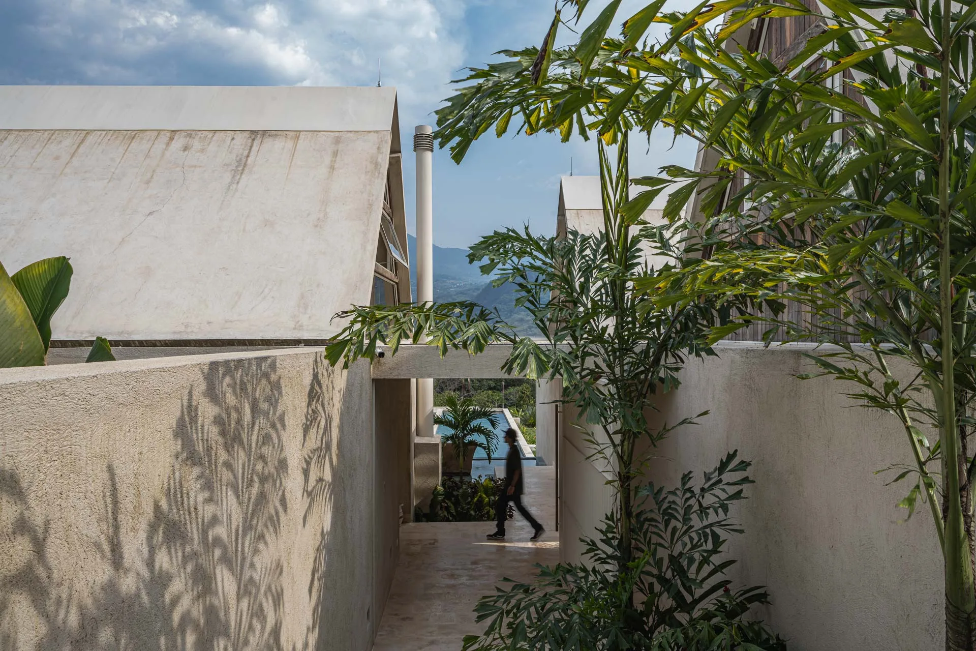 Fachada residencial en concreto pigmentado ocre y vidrio de Casa Siria por Llano Arquitecto en Antioquia.